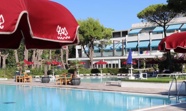 Outdoor pool with red umbrellas and lounge chairs.