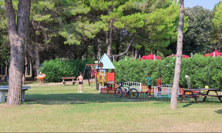 Outdoor playground with children and green trees.