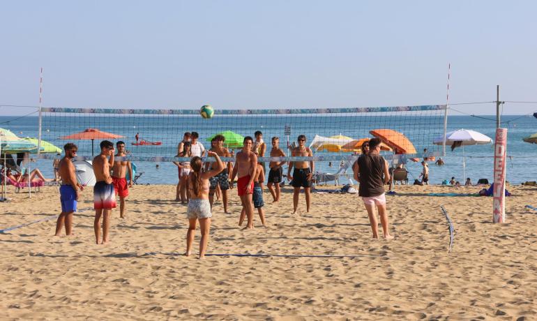Giovani giocano a beach volley sulla spiaggia soleggiata.